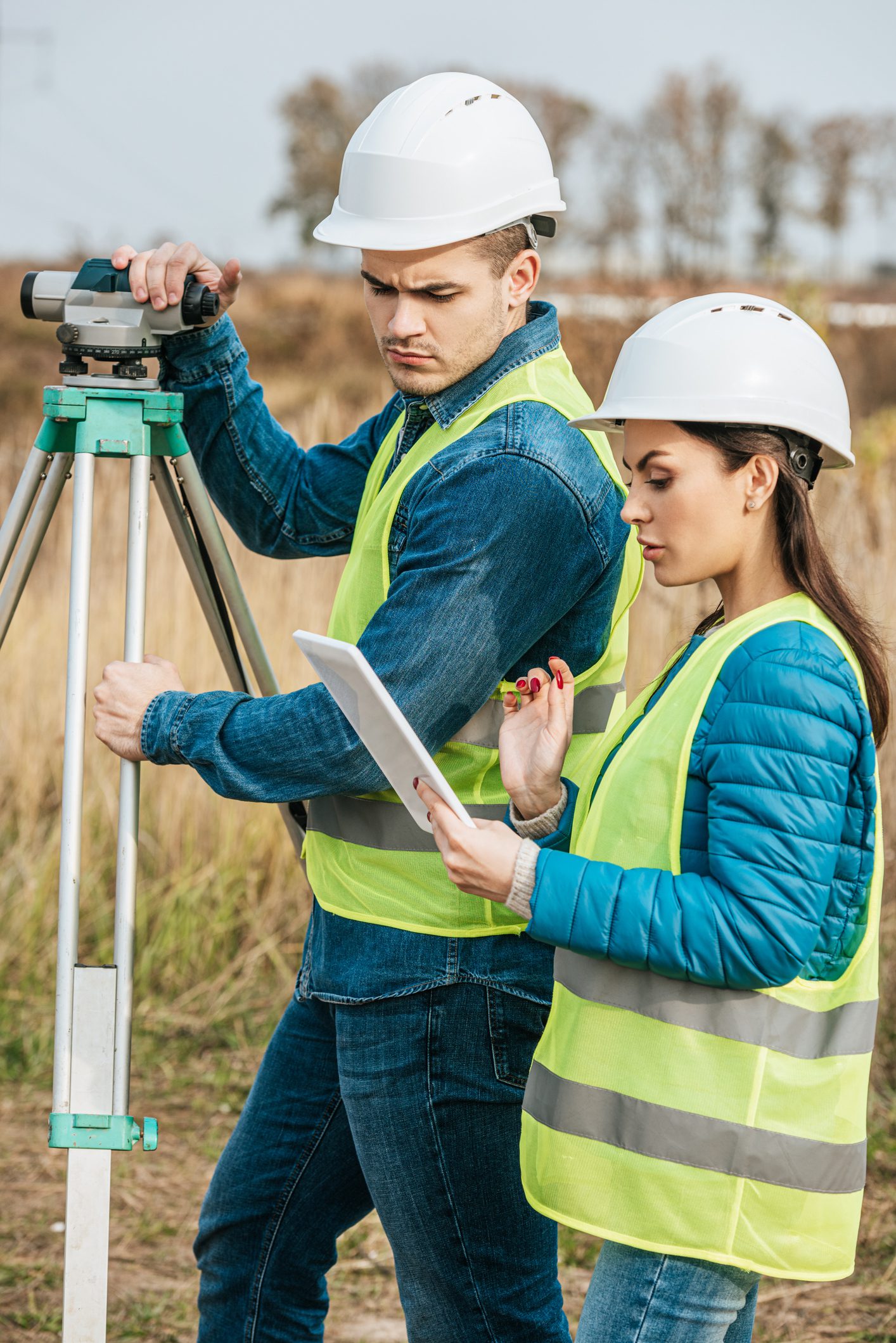 Surveyors with digital level looking at tablet in field