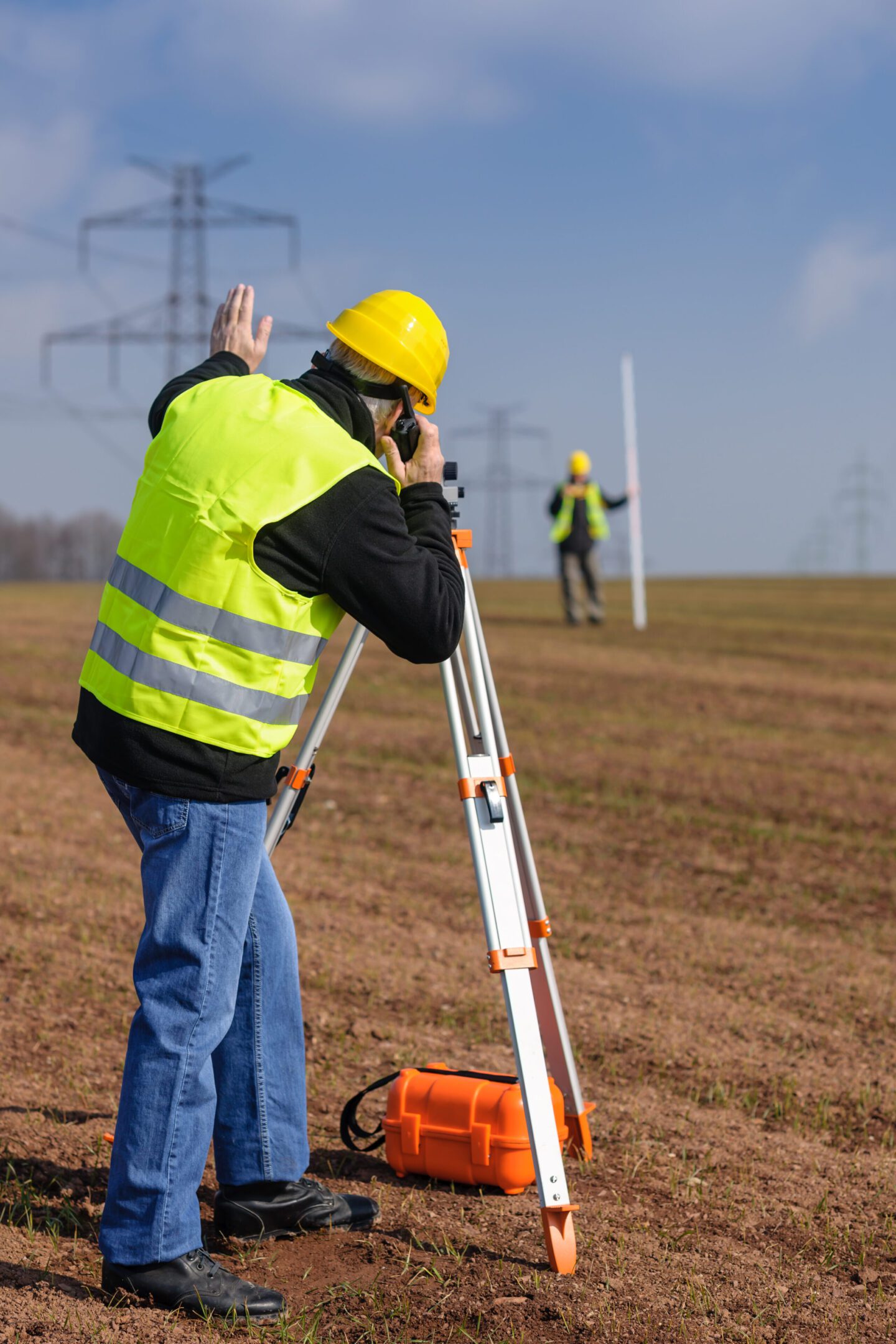 Land surveyors measuring land with theodolite speaking through transmitter